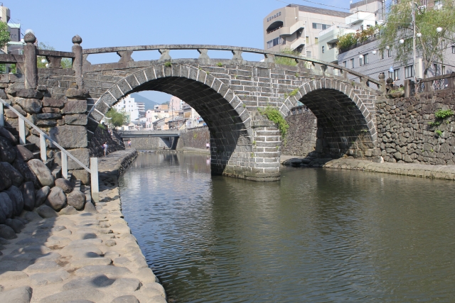 長崎市の眼鏡橋、川沿いの観光名所と背景の街並み